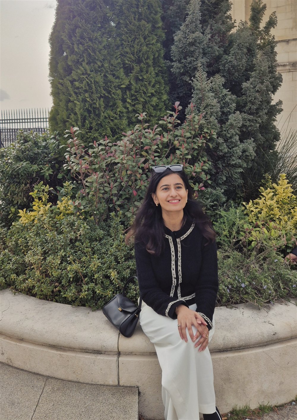 Nikita Gandhi, who researches and writes Worth Keeping, seated outdoors among greenery